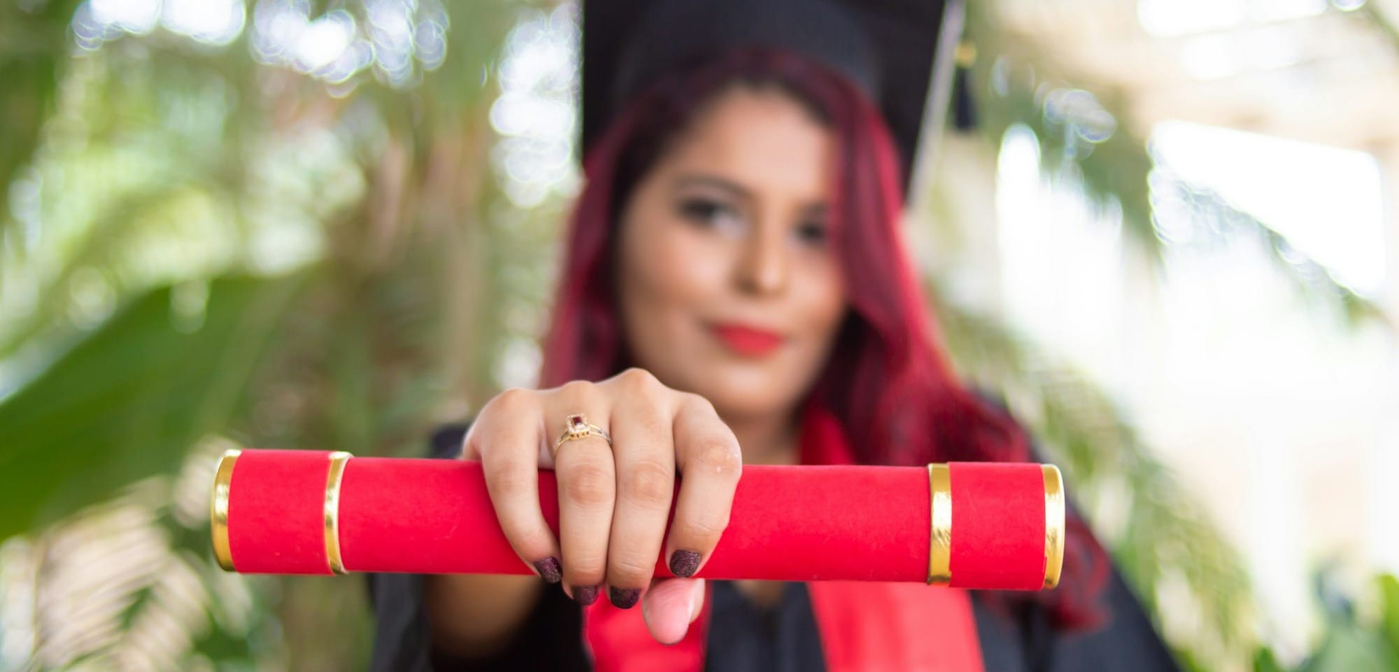 woman in red long sleeve shirt holding red and black academic hat